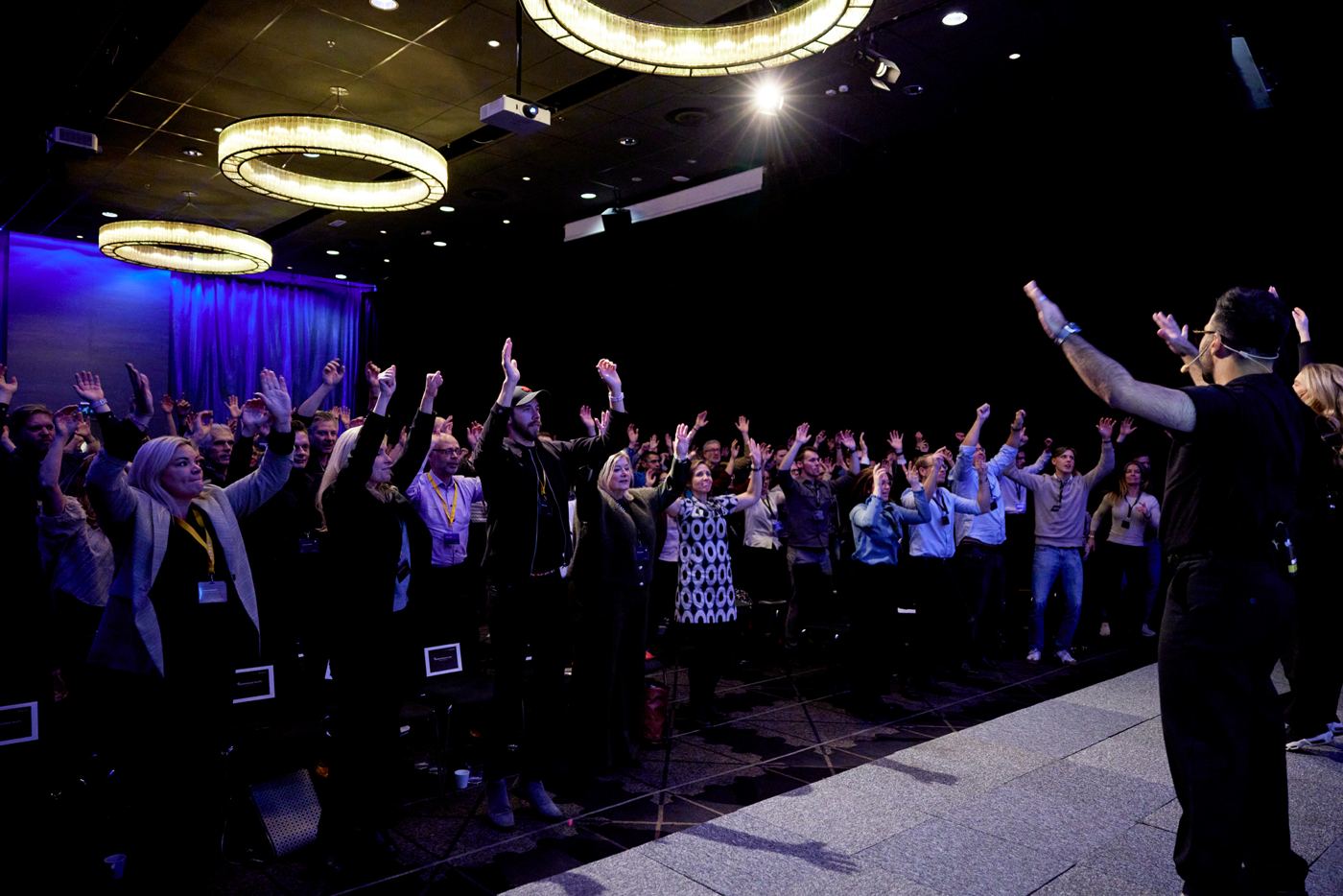 Fullsatt salong i Göteborg med händerna i luften